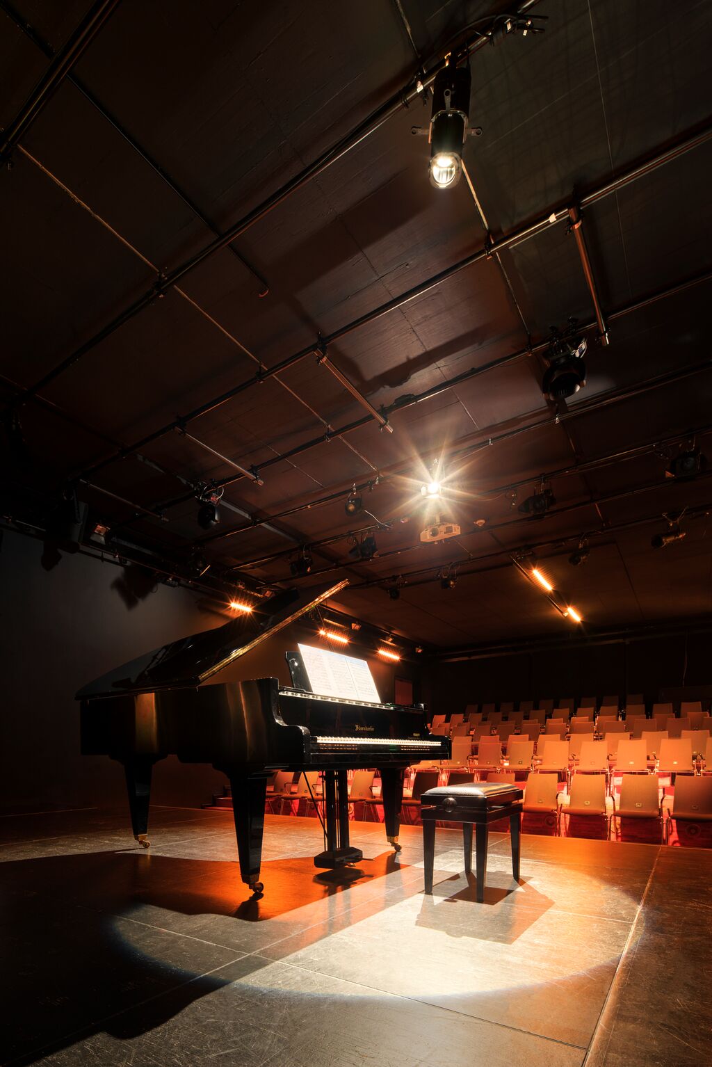 spotlight shining on smal concert stage with piano